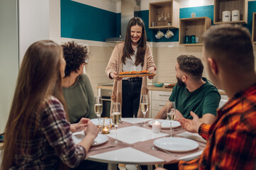 Group of friends enjoying dinner while sitting at the kitchen table together