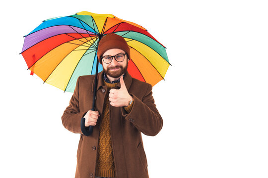  Bearded man giving thumbs up hand gesture to rain weather. Hipster holding colorful umbrella. Rain man. The colorful umbrella never fails to catch the eye. High quality photo 