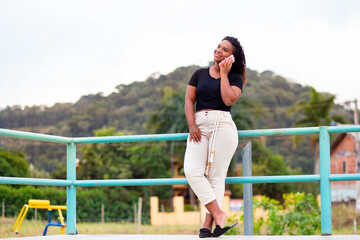 Young happy black woman holding a smartphone.  Using mobile app or social networks on smartphone on the street.