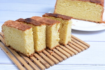 Homemade vanilla cake, displayed on a plate and portioned and on a wooden background