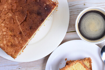 Homemade vanilla cake, displayed portioned and traces of coffee in the background on wood