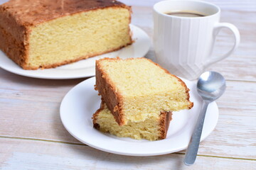 Homemade vanilla cake, displayed portioned and traces of coffee in the background on wood