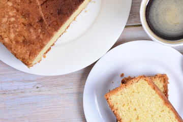 Homemade vanilla cake, displayed portioned and traces of coffee in the background on wood