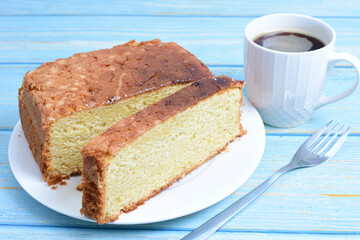 Homemade vanilla cake, displayed portioned and traces of coffee in the background on wood