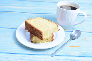 Homemade vanilla cake, displayed portioned and traces of coffee in the background on wood