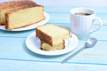 Homemade vanilla cake, displayed portioned and traces of coffee in the background on wood