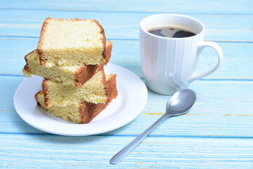 Homemade vanilla cake, displayed portioned and traces of coffee in the background on wood