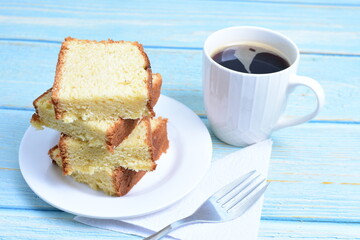 Homemade vanilla cake, displayed portioned and traces of coffee in the background on wood