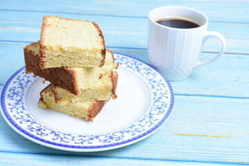 Homemade vanilla cake, displayed portioned and traces of coffee in the background on wood