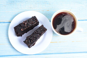 Traditional black ponque, with raisins, red wine flavor accompanied by a cup of coffee on a wooden background