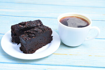 Traditional black ponque, with raisins, red wine flavor accompanied by a cup of coffee on a wooden background