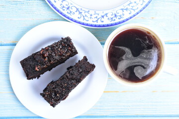 Traditional black ponque, with raisins, red wine flavor accompanied by a cup of coffee on a wooden background