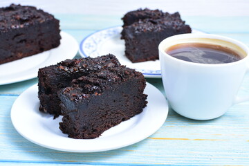 Traditional black ponque, with raisins, red wine flavor accompanied by a cup of coffee on a wooden background