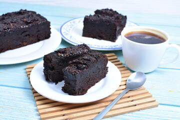 Traditional black ponque, with raisins, red wine flavor accompanied by a cup of coffee on a wooden background