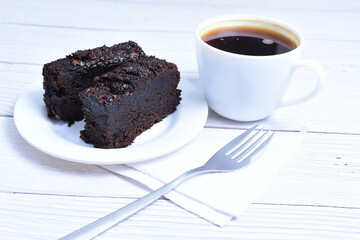 Traditional black ponque, with raisins, red wine flavor accompanied by a cup of coffee on a wooden background