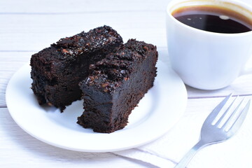Traditional black ponque, with raisins, red wine flavor accompanied by a cup of coffee on a wooden background