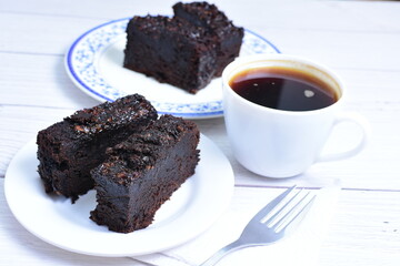 Traditional black ponque, with raisins, red wine flavor accompanied by a cup of coffee on a wooden background
