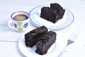 Traditional black ponque, with raisins, red wine flavor accompanied by a cup of coffee on a wooden background