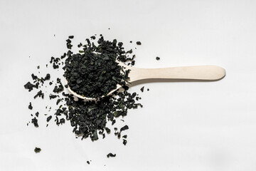dry wakame algae on a white background on a wooden spoon lie
