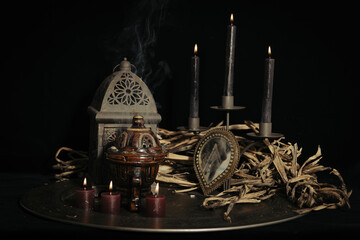 A fortune teller, witch stuff on a table, candles and fortune-telling objects. The concept of...