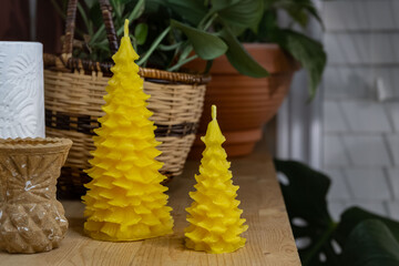 Two beeswax candles shaped like Christmas Trees are being displayed on a shelf with various decor. - obrazy, fototapety, plakaty
