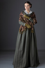 A Victorian working class woman wearing a green checked bodice and skirt with a lace collar and a...