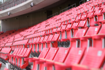 Fototapeta premium Rows of empty red plastic chairs at a sports stadium.