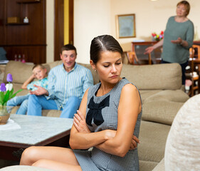 Young woman sitting on sofa at home offended after quarrel with mother and husband