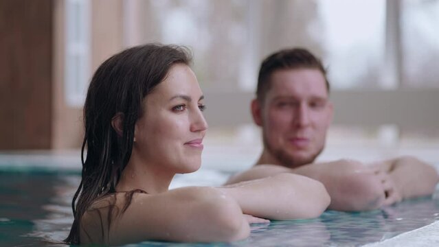 relaxed visitors of modern spa center, happy man and woman are bathing in swimming pool with termal water