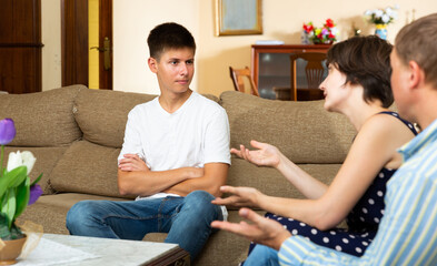 Angry parents scolding their sad young son in living room