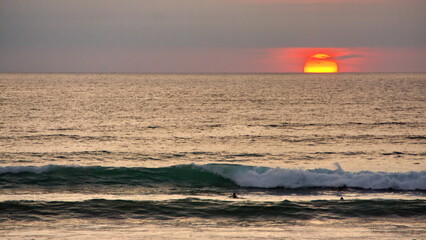 Sunset over the beach in Canoa, Ecuador, silhouetting swimmers