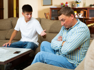 Sad and disappointed man dont speaking with his teen son after discord at home