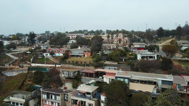 Aerial dolly in of coastal road and Concon apartment buildings in La Boca beach area on an overcast day, Chile