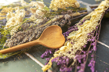 Cooking concept: Close-up of a heart shaped wooden spoon arranged between different flowers on a...