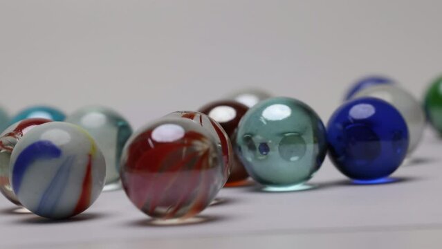 Glass marble balls playing rolling hitting clashing on white background 