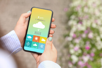 Young woman using weather forecast app in her mobile phone, closeup