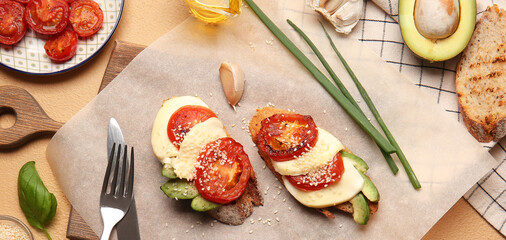 Tasty bruschettas with grilled tomatoes, cheese and avocado on table
