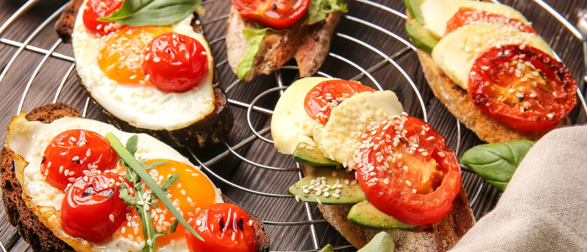 Tasty bruschettas with grilled tomatoes, cheese, egg and avocado on table