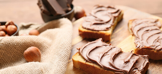 Pieces of fresh bread with chocolate hazelnut butter on wooden board