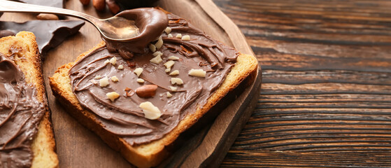 Board with fresh bread and chocolate nut butter on wooden background with space for text