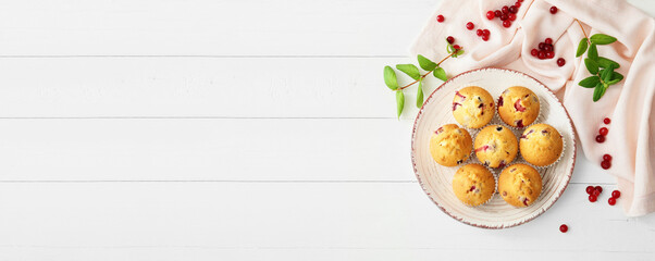 Plate with tasty cranberry muffins on white wooden background with space for text