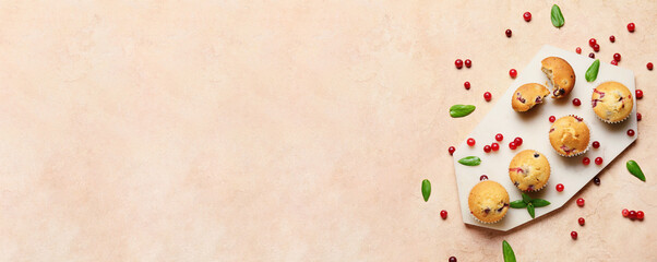 Board with delicious cranberry muffins on light background with space for text