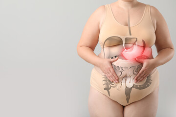 Overweight woman suffering from stomachache on light background with space for text