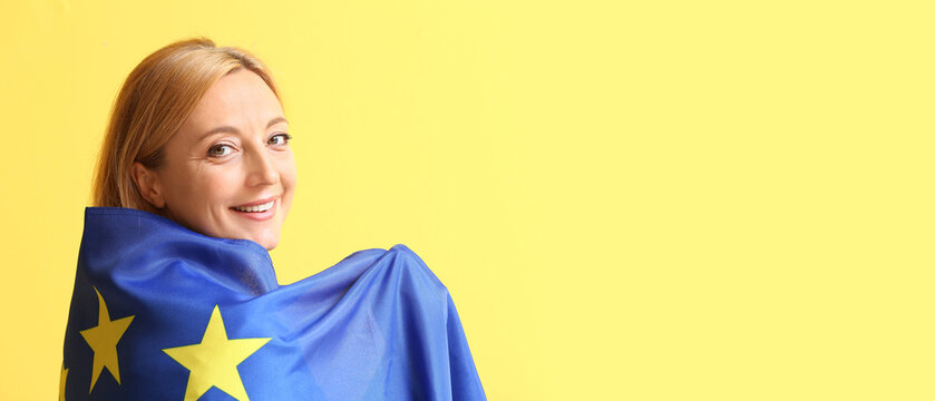 Mature woman wrapped in flag of European Union on yellow background with space for text