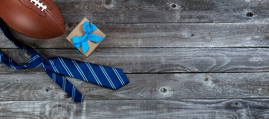 Blue tie, football and giftbox on a vintage wood table for Fathers Day gifts