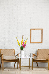 Comfortable armchairs and vase with beautiful gladiolus flowers in room