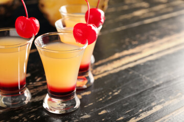 Tasty Pineapple Upside Down Cake Shots on black wooden background, closeup