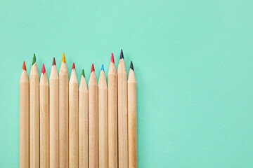 Obraz premium Row of sharpened wooden colored pencils with various lead colors on a mint green background education and creativity, this composition education creativity and artistic expression