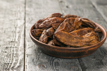 Dried bananas in a clay bowl on a black wooden table.