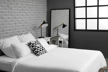 Comfortable bed, modern lamp and mirror in room